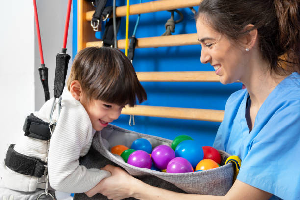 Cute kid with cerebral palsy doing musculoskeletal therapy in the hospital while laughing and having fun . High quality photo